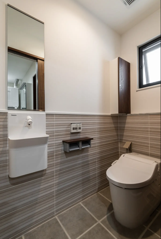 リズミカルな腰壁タイルがアクセントになる、清潔感のあるトイレ空間