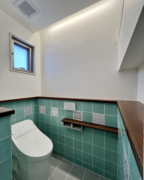 ターコイズタイルがアクセントになる、トイレの腰壁タイル施工例